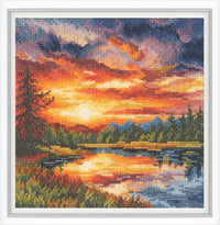 Cross-stitched landscape of a sunset over a lake with trees and mountains.