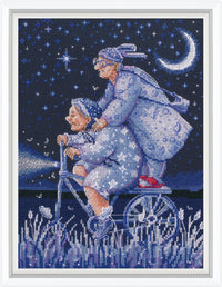 Cross-stitched artwork of an elderly couple in blue pajamas riding a moon-shaped bike under a starry night sky.