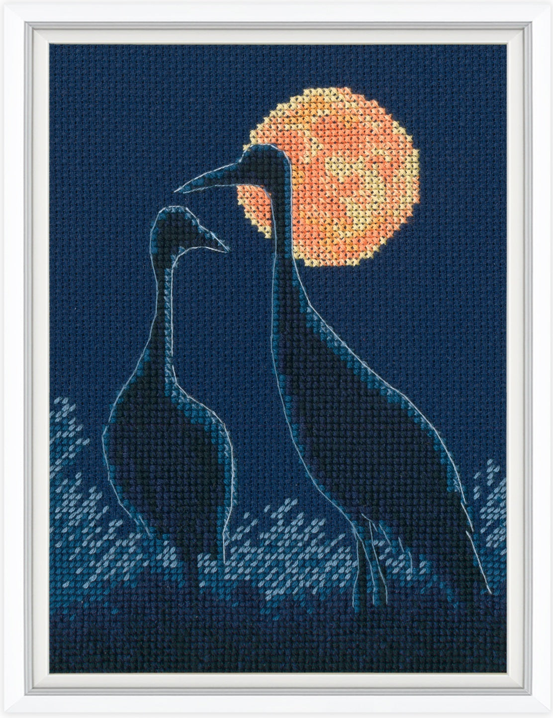 Cross-stitched design of two birds facing each other with a full moon in the background.