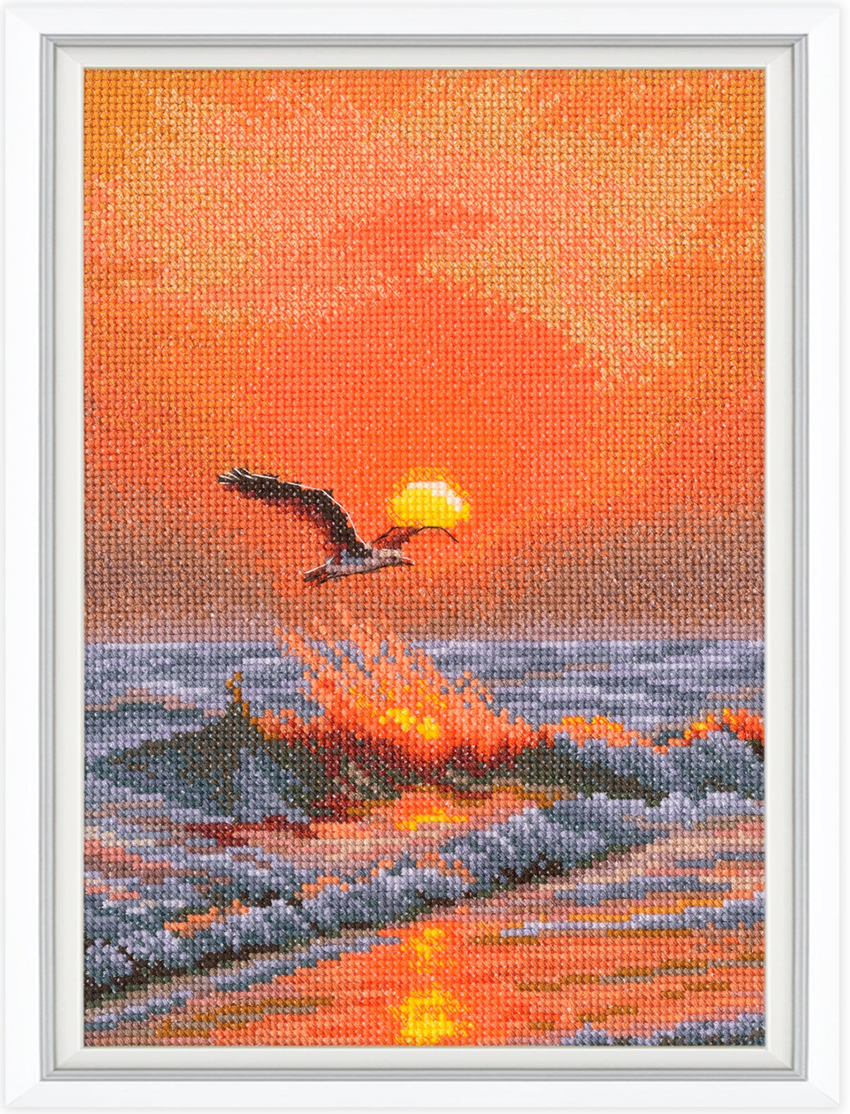 Cross-stitched artwork of a sunset scene with a bird flying over water.